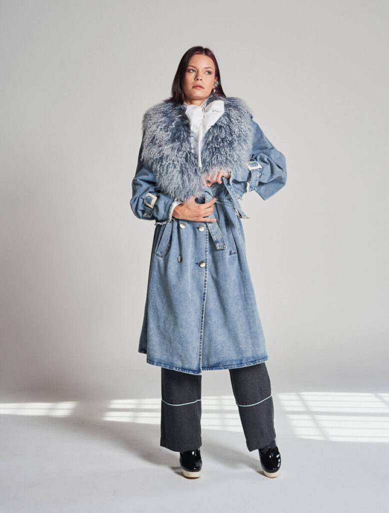 Modelo de pie con el Abrigo Campanilla cerrado por cinturón y gran cuello de piel mongola bicolor.