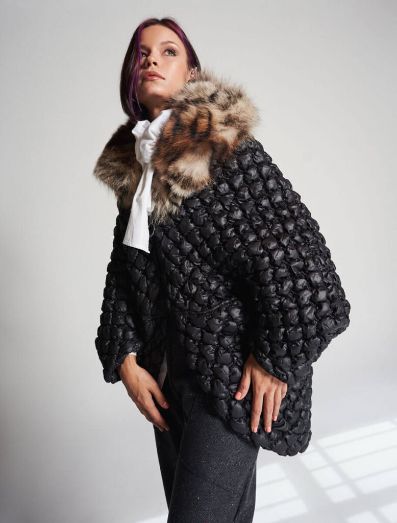 Modelo luciendo la Capa Acebo Negra acolchada con cuello de zorro en tonos animal print.