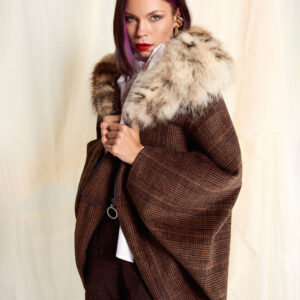 Modelo luciendo la Capa Mimosa Cuadro Marrón con cuello de zorro natural, vista frontal con actitud elegante.