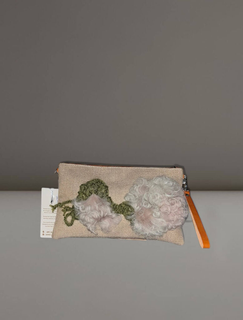 Cartera Peonía de Yes50, bordada a mano con lana en tonos verde, beige y rosa.