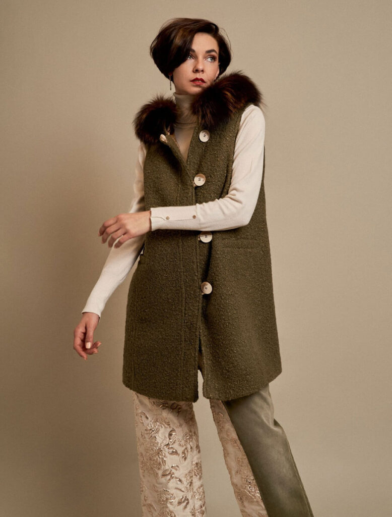 Mujer con chaleco verde de tejido rizado y cuello de zorro, vista frontal.