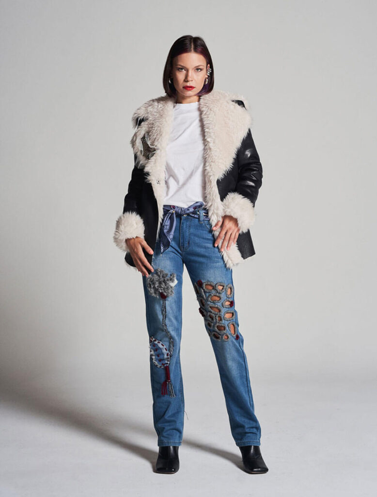 Mujer con vaqueros customizados con aplicaciones artesanales y chaqueta de piel blanca y negra